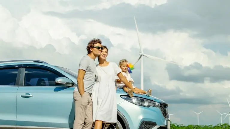 Famille en vacances près d’un parc éolien avec leur voiture électrique