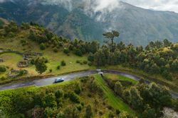 Voiture électrique roulant sur une route de montagne entourée de végétation dense.