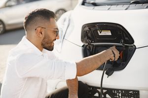 Young man charging his electric car, a symbol of sustainable urban electromobility.