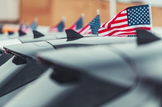 Electric vehicles parked in front of American flags, representing the US EV market.